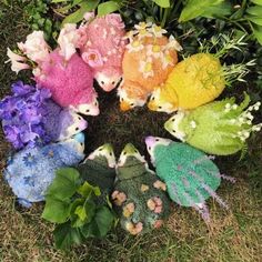 a group of colorful stuffed animals sitting on top of a grass covered field next to flowers