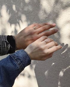 a woman's hand with two rings on her fingers, against a gray wall