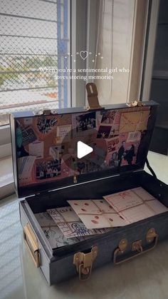 an open suitcase sitting on top of a table next to a window with pictures in it