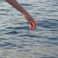 a person reaching for something in the water with their hand on top of the water