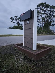 a mailbox sitting on the side of a road in front of some grass and trees