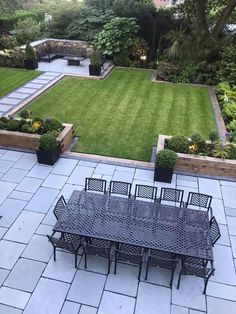 an outdoor dining table and chairs in the middle of a large yard with lawns