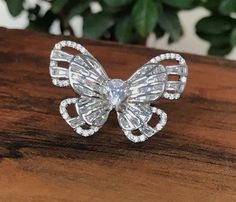 a diamond butterfly ring sitting on top of a wooden table