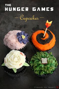 four decorated cupcakes sitting on top of a black table with white frosting