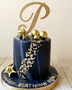 a blue cake with gold stars and a number one on it's top is sitting on a wooden table