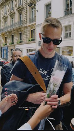 a man in sunglasses is handing flowers to someone