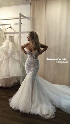 a woman standing in front of a wedding dress