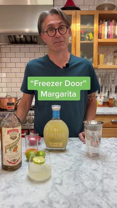 a man standing in front of a counter with bottles and glasses on it that says freezer door margarita