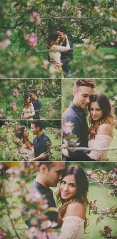 a man and woman hugging in the middle of some trees with pink flowers on them