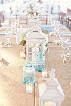 a long table with candles and lanterns on it is set up for a wedding reception