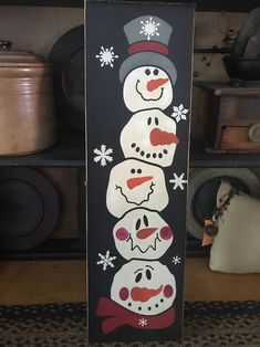 a snowman is standing next to two other snowmen on a black board with white snowflakes