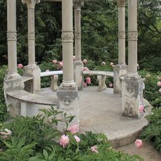 the gazebo is surrounded by pink flowers and greenery