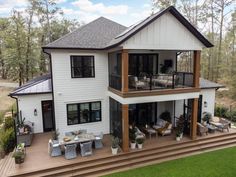 an aerial view of a large white house with decking and outdoor furniture in the foreground