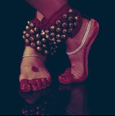 a woman's feet with red shoes and beads on them