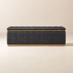 an upholstered bench with wooden legs and black leather cushioning, in front of a beige wall