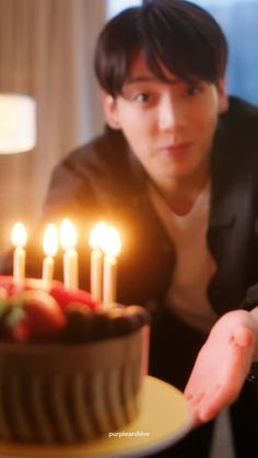 a young man is blowing out candles on a cake