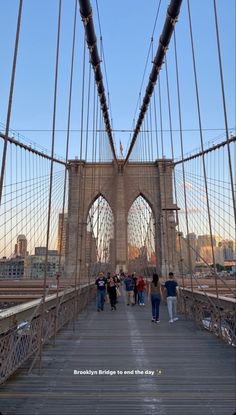 people walking across the brooklyn bridge on a sunny day