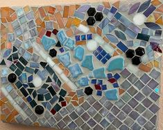 a mosaic tile wall hanging on the side of a building with lots of different colors and shapes