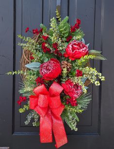 a wreath with red flowers and greenery on the front door