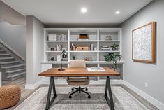 a home office with built - in shelving and desk area, along with stairs