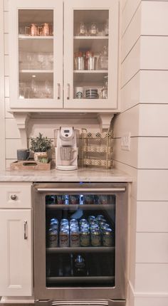 an open refrigerator in a kitchen with white cabinets and glass doors on the front door