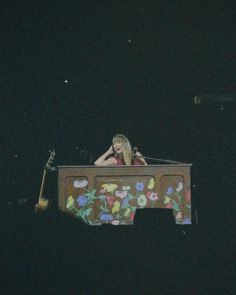 a woman sitting on top of a wooden table covered in flowers at the end of it