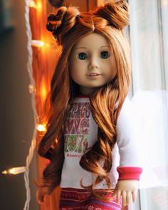 a doll with long hair standing next to a window