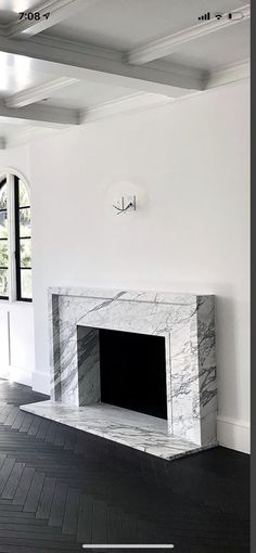 an empty living room with a fireplace in the middle and black tile on the floor