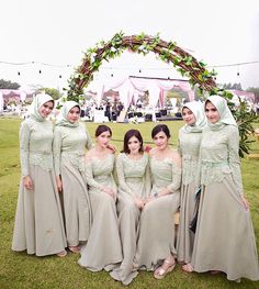 the bridesmaids are posing for a photo in front of an arch decorated with greenery