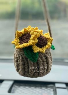 a crocheted sunflower hanging from a car dashboard