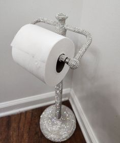 a white toilet paper roll sitting on top of a metal stand next to a wall