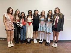 a group of young women standing next to each other on a brick floor in front of a white wall