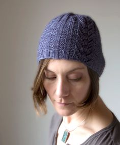 a woman with her eyes closed wearing a blue knitted beanie and looking down