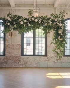 an empty room with large windows and flowers hanging from the ceiling