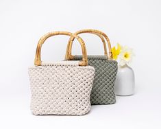 two woven purses sitting next to each other on a white surface with a yellow flower in the background