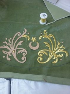 a piece of green fabric with gold designs on it