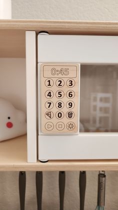 a white microwave oven sitting on top of a wooden shelf next to a stuffed animal