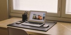 an open laptop computer sitting on top of a desk next to a cup and pen