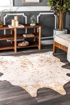 a living room area with a rug, table and plant in the corner on the floor