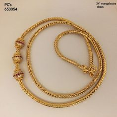 a gold necklace with beads on a white background