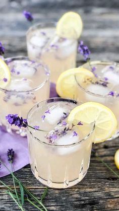 three glasses filled with lemonade and lavender sprits on top of a wooden table