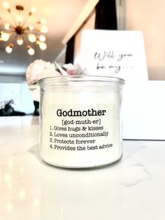 a white candle sitting on top of a counter next to a sign that says godmother