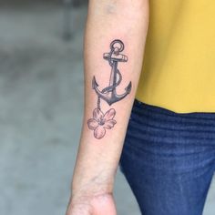 a woman's arm with an anchor and flower tattoo on it