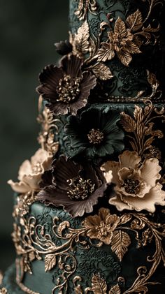 a green and gold wedding cake with flowers on the top tier, decorated with filigree leaves