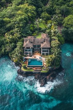 an aerial view of a house in the middle of some water with trees around it