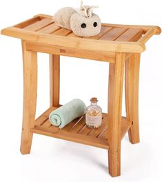 a small wooden table with towels and soaps on the top, next to a stuffed animal