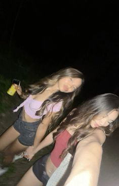 two girls are walking down the street at night