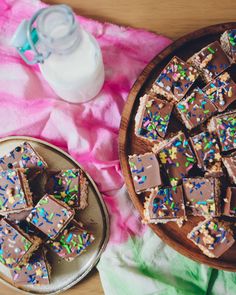 a plate full of chocolate and sprinkles next to a bottle of milk