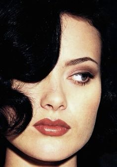 a close up of a woman's face with dark hair and red lipstick on