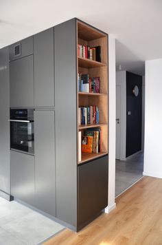 a kitchen with an oven, bookshelf and cabinets in the middle of it